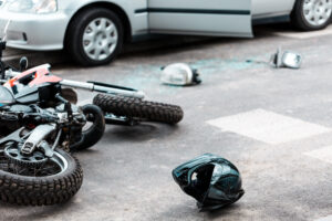 motorcycle on its side with helmet next to it after being hit by car.